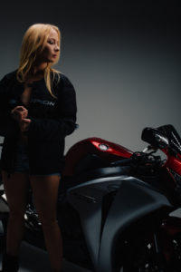 Female model posing next to a sport motorcycle.